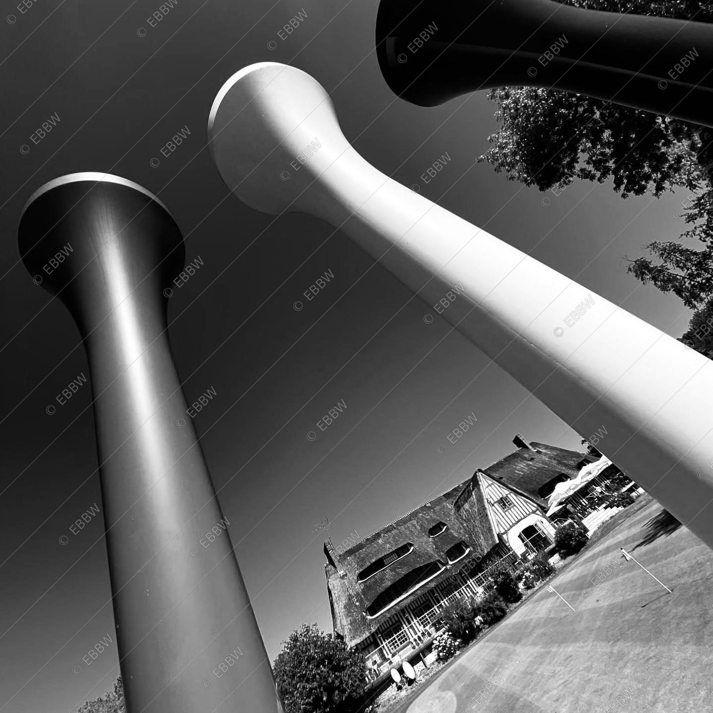 Sculptures en forme de colonnes devant un club-house à toit de chaume