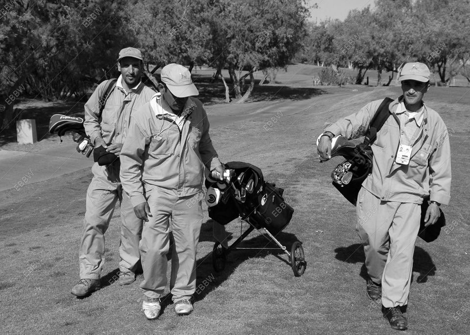 Trois caddies marchant sur le parcours avec les sacs de golf